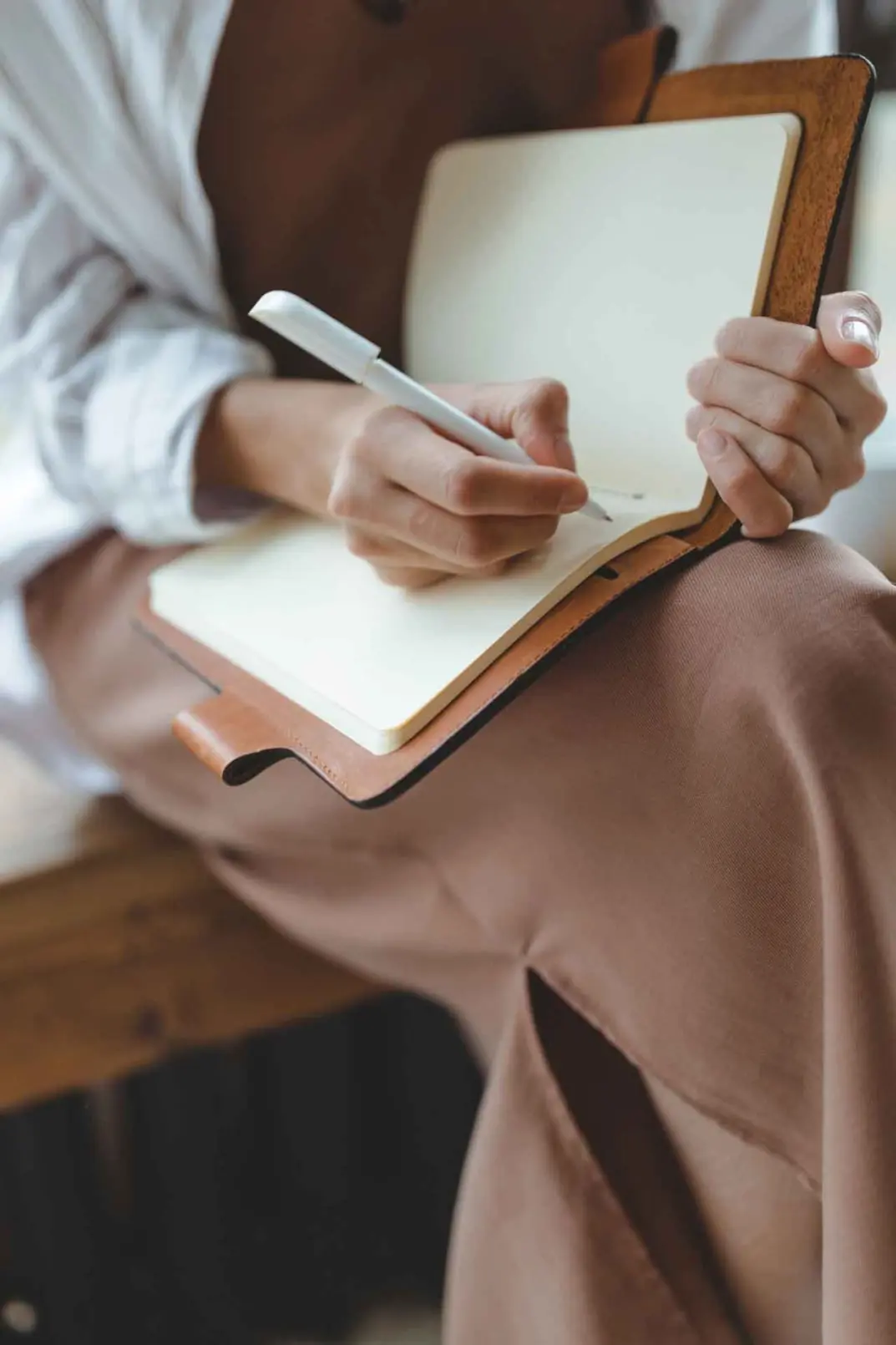 Hand einer Frau, Stift und offenes Notizbuch