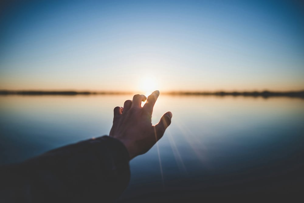 Hand einer Person vor der Sonne - Spirituelle Psychotherapie: Eine Verbindung zu etwas Größerem